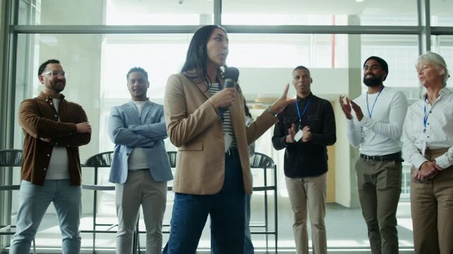 A female speaker engages a group of attentive professionals during a conference or business event. Her presentation fosters connection and shared understanding among colleagues.