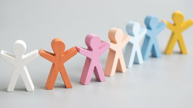 Row of colorful wooden human figures standing in line on grey surface symbolizes diversity and inclusion for corporate team building or social community projects.