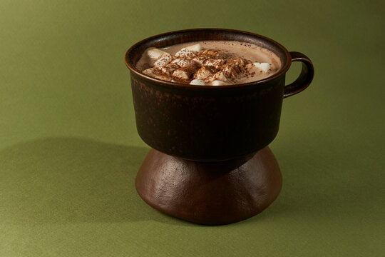 Hot Chocolate with Marshmallows in Dark Mug on Ceramic Stand