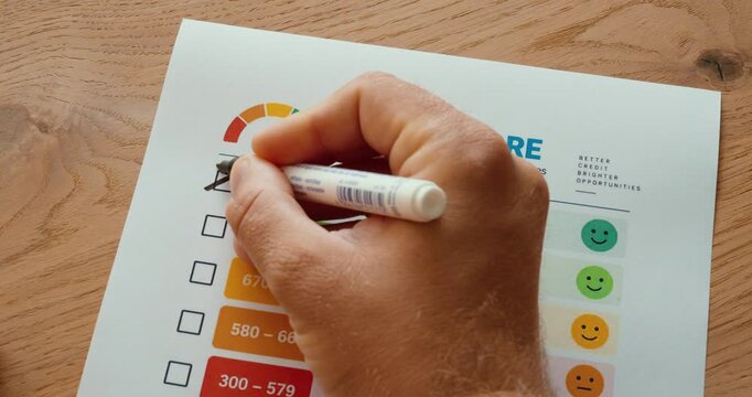 Person marking the excellent credit score range on a credit rating checklist with a pen.