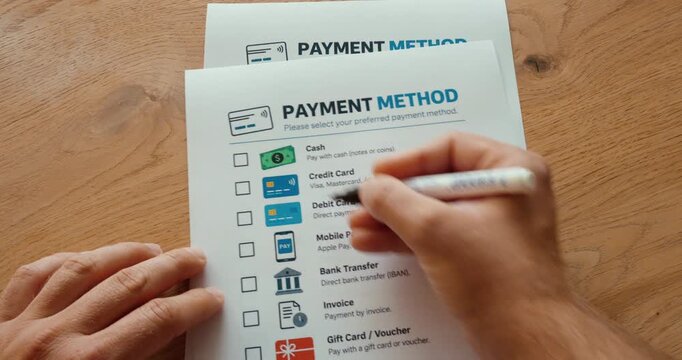 Person marking cash as the preferred payment method on a payment options checklist.