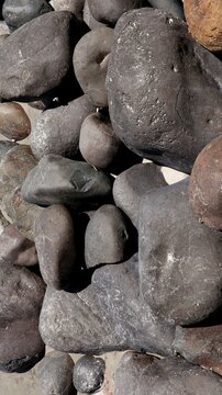 Top-down close-up of smooth, dark volcanic river stones and rounded pebbles piled together.