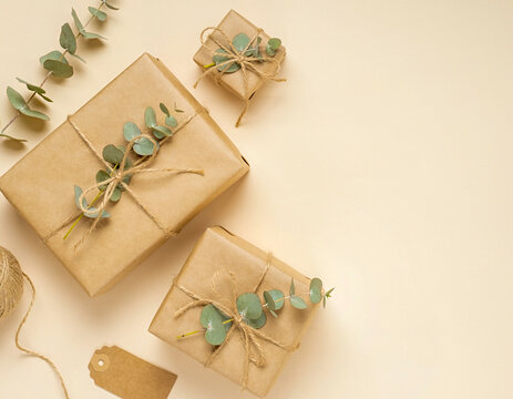 Minimalistische Geschenke verpackt mit Packpapier und Eukalyptus auf hellem Grund