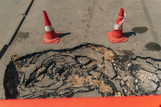 Close-up of a deep pothole with cracked asphalt on a city road.