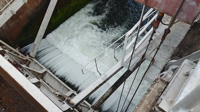 A large water release gate at a dam controlling the flow of water through a reservoir and downstream channel.