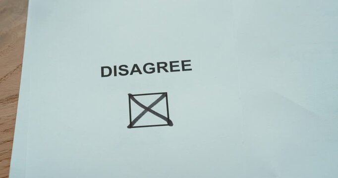 Person marking disagree on a checkbox, representing disagreement, rejection and a negative decision.