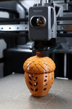 3D printer creating a decorative acorn layer by layer using additive manufacturing technology. Close-up of a 3D printer creating a decorative acorn during the additive manufacturing process.