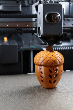 3D printer creating a decorative acorn layer by layer using additive manufacturing technology. Close-up of a 3D printer creating a decorative acorn during the additive manufacturing process.