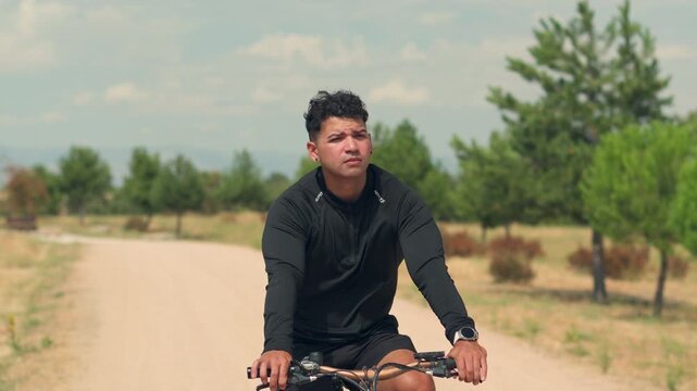 Young man stops cycling to check smartwatch during outdoor bike workout