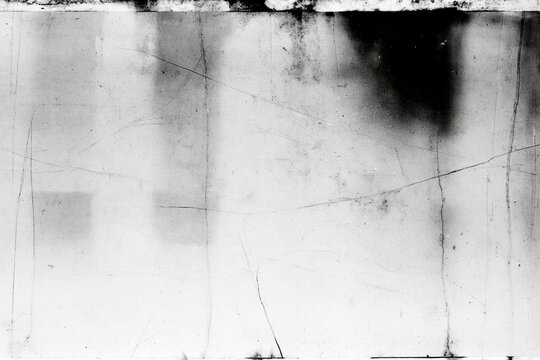 Distressed black and white film frame with faded stains, scratches and weathered surface, abstract vintage grunge texture for photo overlay and graphic design