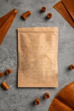 Natural fruit leather rolls and sheets arranged around craft paper ziplock pouch mock up on grey concrete background