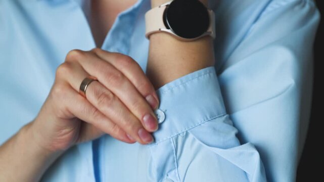Close-up of a person fastening a button on a blue shirt cuff
