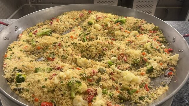 Vegetarian paella with rice and vegetables in a large restaurant frying pan. Colorful, aromatic, delicious, freshly made.