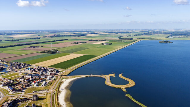 Aerial view of Tulpeiland, a tulip-shaped artificial island in Wolderwijd lake, surrounded by polder landscapes, wind turbines, and residential areas in Wolderwijd, Flevoland, Netherlands.