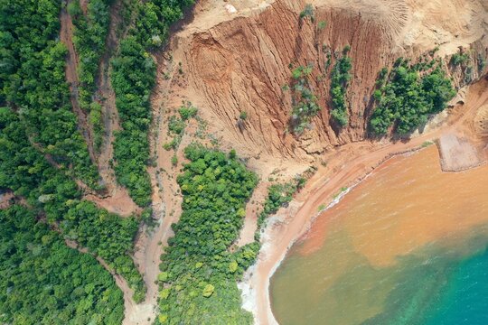 Aerial view of PT Ceria Nugraha Indotama mining site showing red soil excavation, deforestation, and sediment runoff into the coastal waters in Wolo, South East Sulawesi, Indonesia.