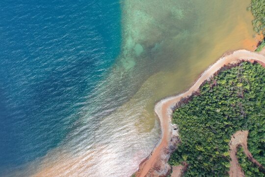Aerial view of the PT Ceria Nugraha Indotama mining site coastline showing sediment runoff entering the blue sea near the forested landscape in Wolo, South East Sulawesi, Indonesia.