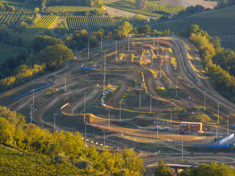 Aerial view of the Monte Coralli motocross track featuring winding dirt paths, steep hills, and surrounding vineyards in the rural landscape of Faenza, Emilia-Romagna, Italy.