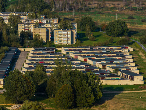 Aerial view of rows of garages and residential apartment buildings surrounded by trees and green space in Kaisiadorys, Kaunas County, Lithuania.