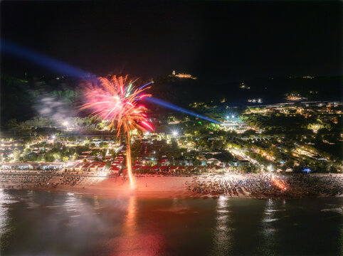 Aerial view of fireworks illuminating the night sky over Villaggio Turistico Verde Mare resort on the beach in Fermo, Marche, Italy.