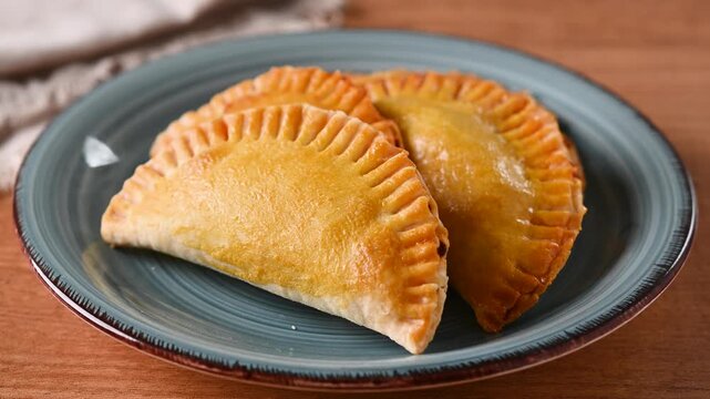 Plate filled with golden homemade empanadas, traditional savory pastries served as a snack, appetizer or meal.