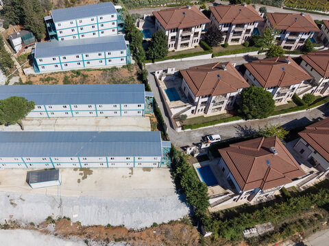 Aerial view of modern residential houses with swimming pools situated next to rows of modular prefabricated buildings in Izmit, Kocaeli, Turkey.