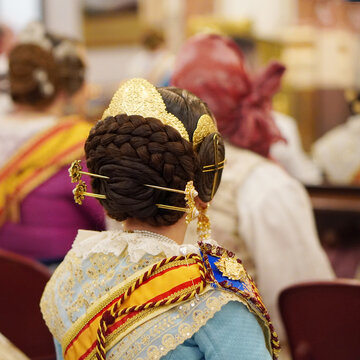 Traditional hairstyle of a Valencian fallera, featuring a back bun, a gold comb and side coils