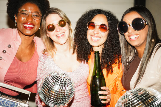 Group of multiracial girls dancing, drinking champagne and listening music outdoor - Party, new year's eve and street nightlife concept - Main focus on center girl face - UGC flash content