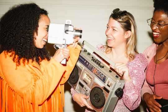 Group of multiracial girls having fun listening music while taking video with a vintage super 8 camera outdoor - Party, nightlife and people lifestyle concept - Main focus on center girl face