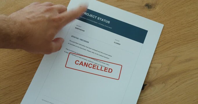 Person slides a project status document into view and points at a cancelled stamp, highlighting a terminated project decision.