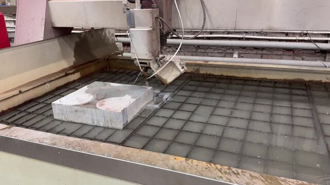 Thick aluminum plate sliced by waterjet cutter with high-pressure abrasive stream, creating precise clean edges without heat distortion.