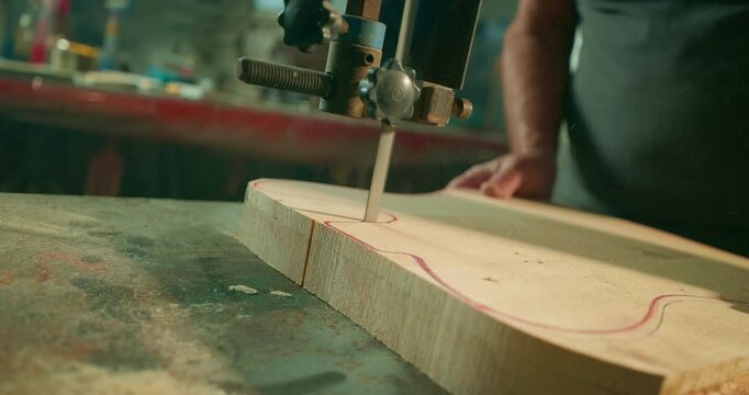 Industrial woodworking machine cutting a wooden board in a luthier's workshop, showing precision engineering, skilled craftsmanship and the transformation of raw wood into a musical instrument.