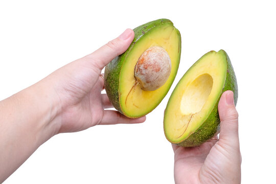 Human hands holding fresh ripe avocado halves isolated on a white background