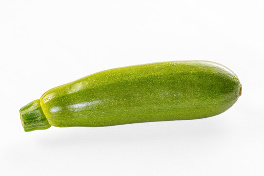 Fresh green zucchini isolated on white background, smooth skin texture, natural lighting, copy space