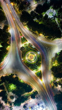 Aerial view of a brightly illuminated roundabout with vibrant light trails from traffic at night in Surabaya, East Java, Indonesia.