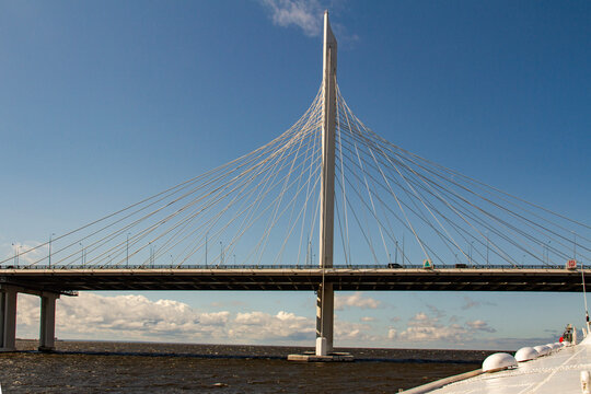 A striking low-angle view of the monumental cable-stayed bridge over the fairway on the Western High-Speed Diameter highway in Saint Petersburg, featuring a towering central pylon against blue sky