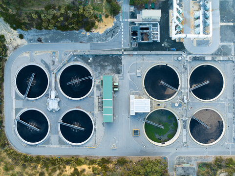 Aerial view of a wastewater treatment plant featuring large circular sedimentation tanks and industrial infrastructure in Perth, Western Australia, Australia.
