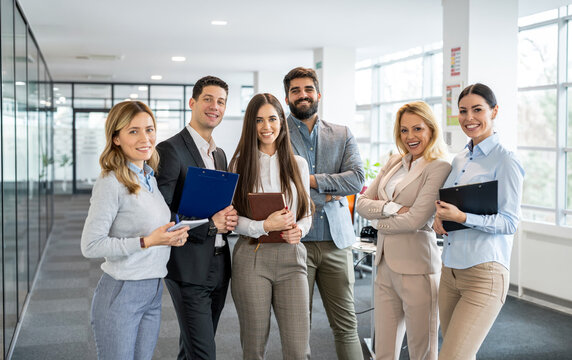 Group of successful young business professionals standing together in office corridor
