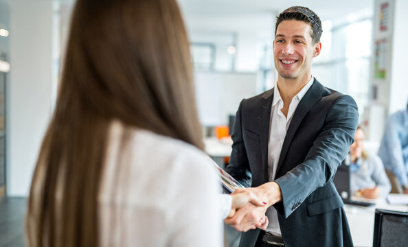 Businessman shaking hands with female colleague after successful agreement in office