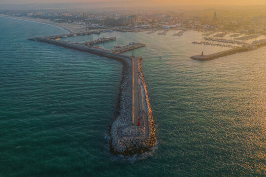 Aerial view of the harbor and breakwater in Civitanova Marche at sunset with boats moored in the marina and the coastal town in the background, Civitanova Marche, Marche, Italy.