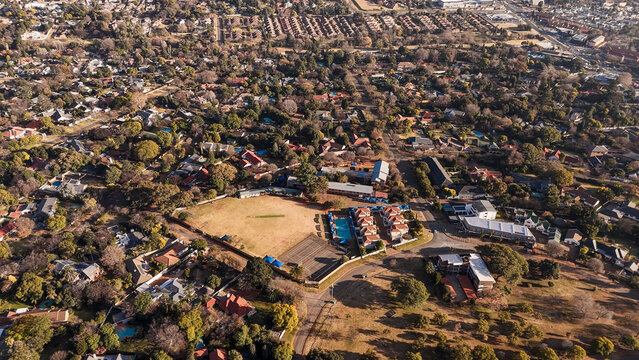 Aerial view of an urban recreational park and sports complex with a cricket field, cricket pitch, and courts nestled within a residential suburb in Johannesburg, Gauteng, South Africa.