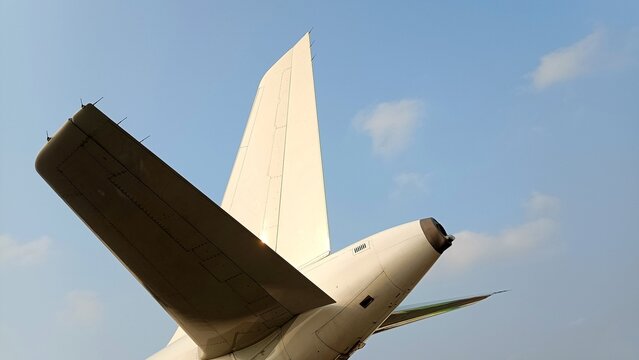 Detailed low-angle view of an aircraft tail section featuring the rudder, vertical stabilizer, horizontal stabilizer, and APU exhaust, highlighting the aerodynamic design and engineering precision