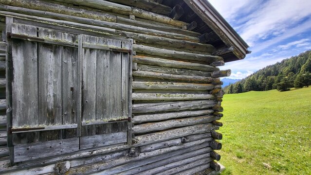 Close-up of an old weathered wooden hut with closed wooden shutters in the Swiss Alps. The aged timber, rustic facade and traditional details create an authentic alpine character.