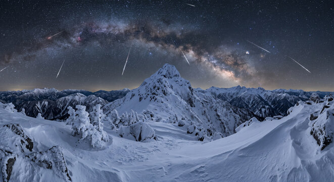 流れ星と天の川が輝く雪山の夜景