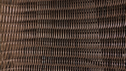 Zbliżenie na gęsty, regularny splot wykonany z ciemnobrązowej wikliny. Zdjęcie ukazuje powtarzalną i precyzyjną strukturę plecionki, charakterystyczną dla tradycyjnych wyrobów rzemieślniczych.