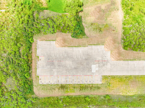 Aerial top down view of a concrete platform surrounded by green grass with paved surface industrial site concrete slab landscape outdoors construction foundation environment daylight