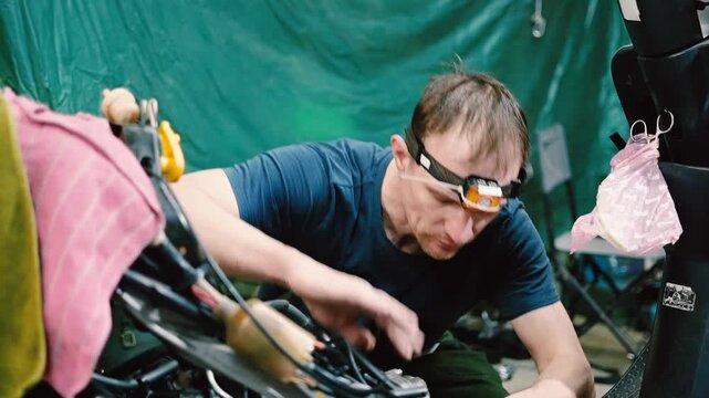 Skilled Mechanic Repairing Scooter Engine in Workshop with Headlamp