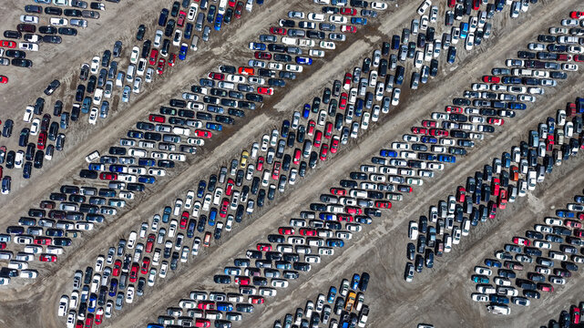 Aerial view of a large outdoor vehicle storage lot filled with rows of parked cars arranged in diagonal lines on a dirt surface in Columbus, Ohio, United States.