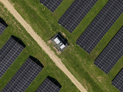 The Basin, Victoria, Australia - 18 September 2026: Aerial view of a solar farm with rows of photovoltaic panels on green grass, separated by a dirt path and electrical equipment.