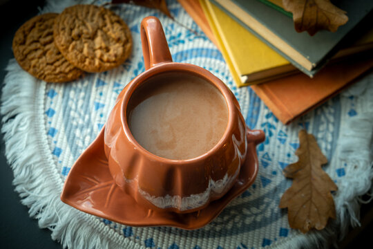 Autumn vibes. Mug of hot chocolate or cocoa, cookies and books on table. Warm cozy fall atmosphere