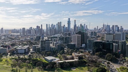 Fototapeta premium Melbourne, Victoria, Australia – 4K aerial drone view of CBD skyline, Southbank skyscrapers, modern high-rise towers, residential suburbs and spectacular urban cityscape under blue sky